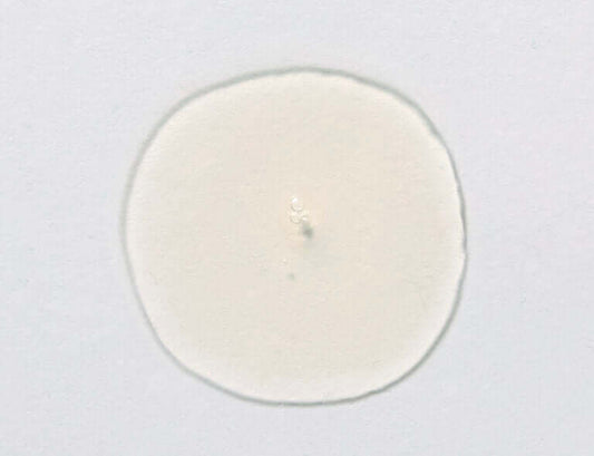 Glycolic cleanser foamy texture detail, showing a small drop on a smooth surface for skin renewal and exfoliation.