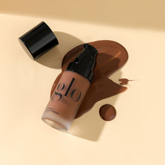 Luminous Liquid Foundation SPF 18 bottle with spill showcases its lightweight, longwearing mineral formula for radiant, protected skin.