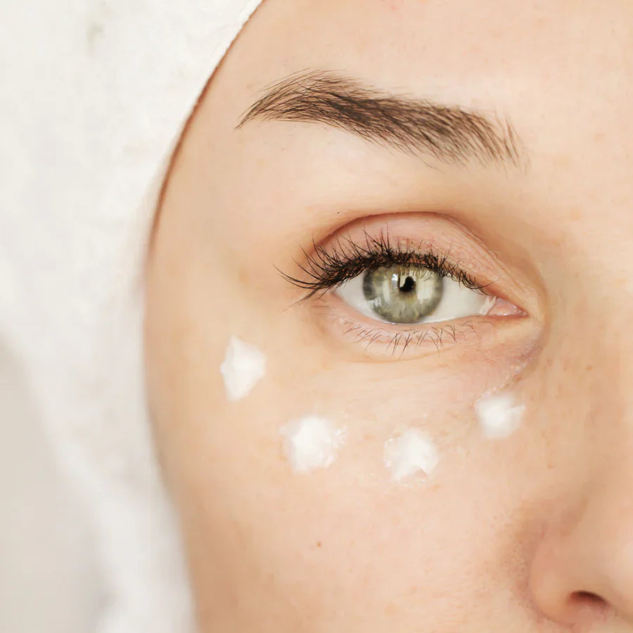 Woman applying eye contour serum to reduce dark circles and puffiness near her eye