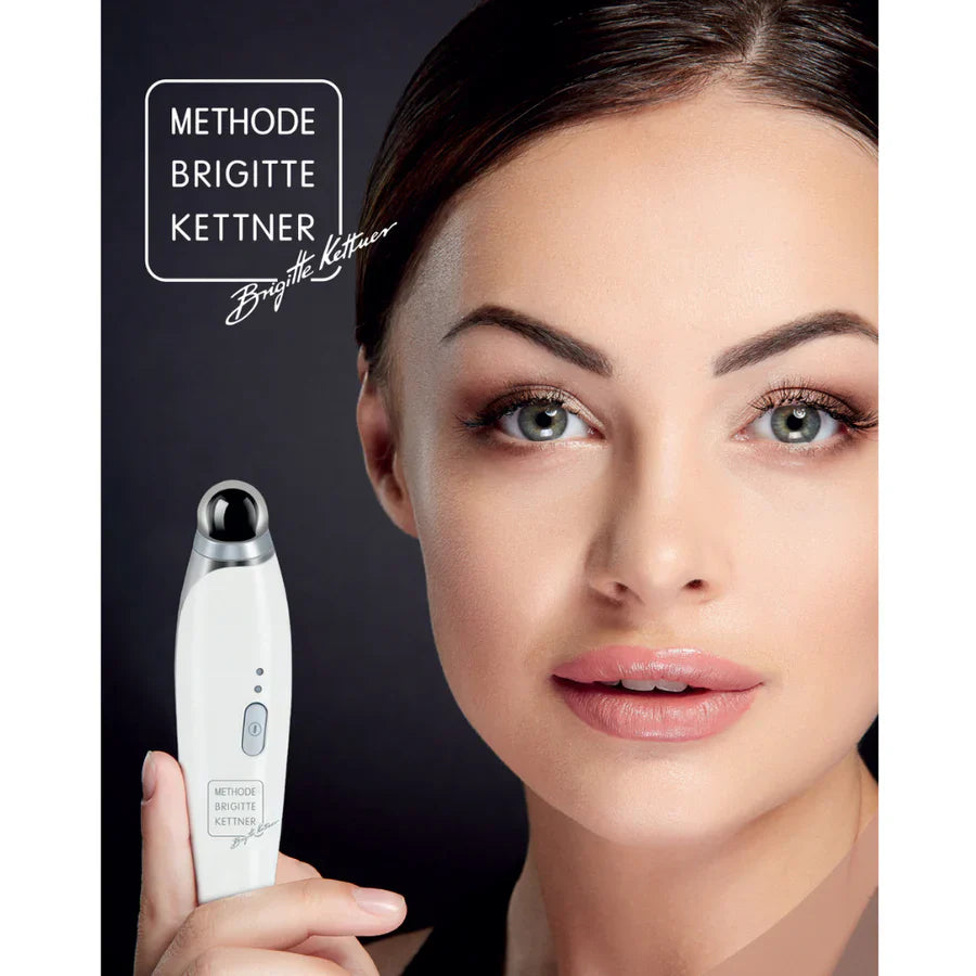 Woman demonstrating MBK Eye Rejuvenator microcurrent device for reducing under-eye puffiness and dark circles.