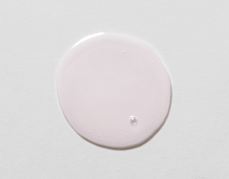 Close-up of a drop of Raspberry Refining Cleanser on a white background, showcasing its smooth texture and pastel pink color.