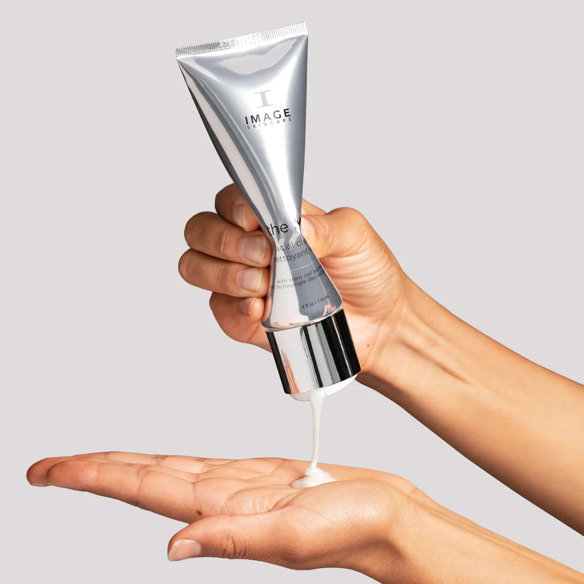 A hand dispensing The MAX™ Facial Cleanser, highlighting its creamy texture in a stylish tube.