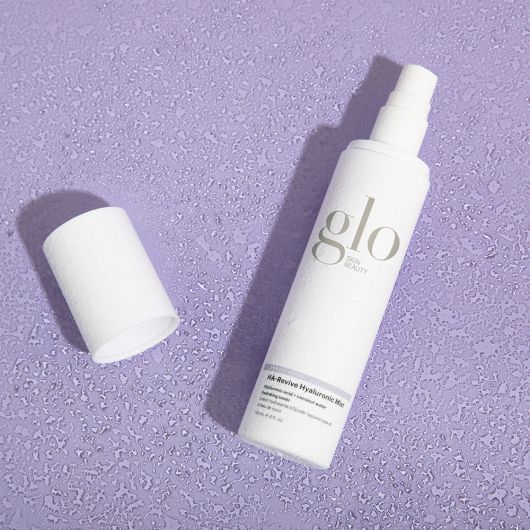 HA-Revive Hyaluronic Mist bottle on a textured lavender background.