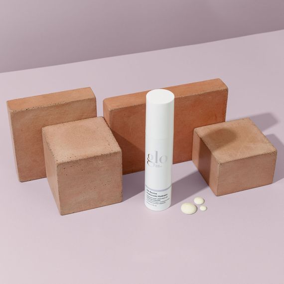 HA-Revive Hyaluronic Hydrator moisturizer bottle placed among wooden blocks on a pink background.