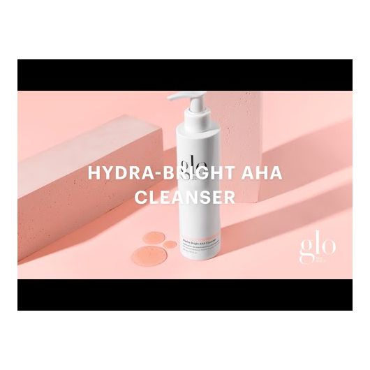 Hydra-Bright AHA Cleanser bottle against a pink background removing makeup and impurities for hydrated, brightened skin adjacent to product blocks