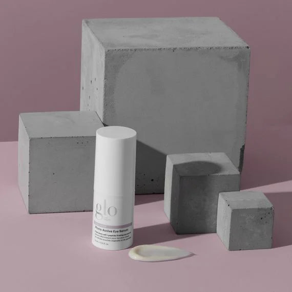 Phyto-Active Eye Serum bottle displayed with grey geometric blocks and product swatch on pink background.