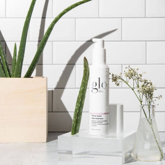 Phyto-Calm Aloe Hydrator bottle placed beside aloe vera plant and flowers, providing soothing and hydrating skincare benefits.