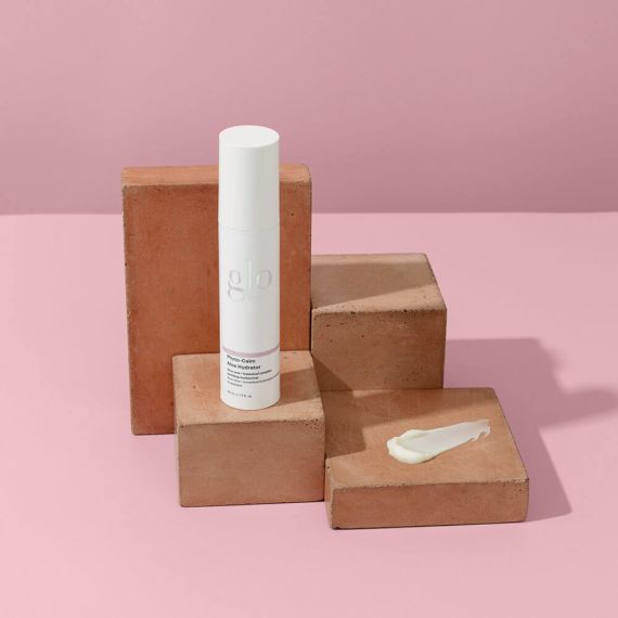 Phyto-Calm Aloe Hydrator moisturizer bottle and cream on terracotta blocks with a pink background.